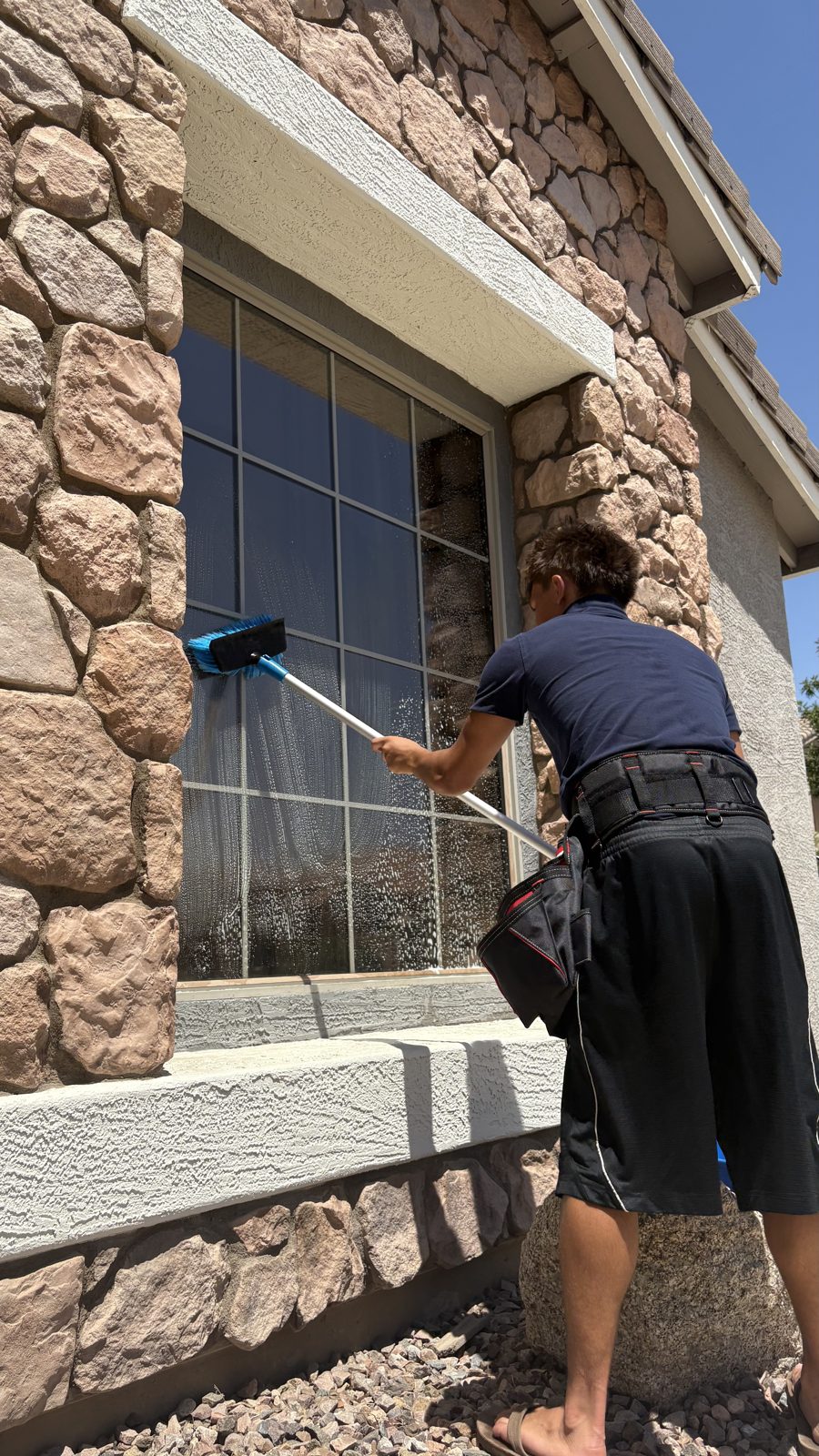 Cactus Clear Windows crew member scrubbing a grid-pane window on a stone East Valley home